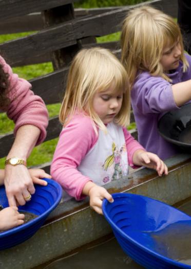 three children panning for gold with two adults helping