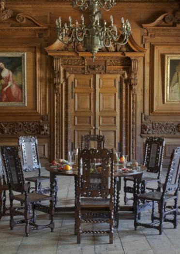 Speisesaal mit Holzvertäfelung und Wandmalereien, Kronleuchter, Holztisch und Stühlen