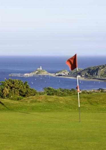 A flag in the hole on the green at Clyne Golf Club overlooking the Gower Peninsula.