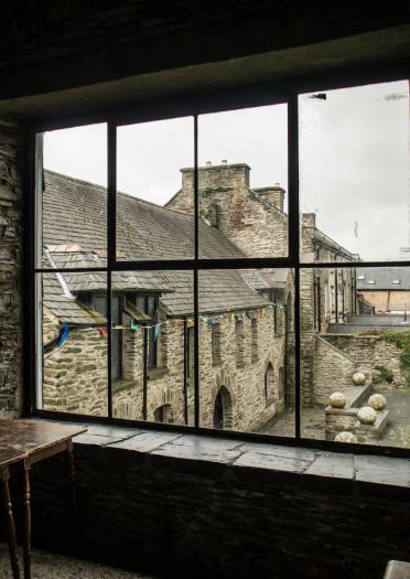 Ausblick aus einem Fenster auf einen kleinen Innenhof mit steinernen Gebäuden drum herum.