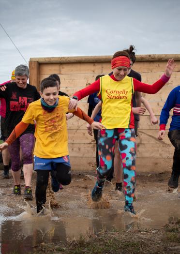 Adults and children running through mud