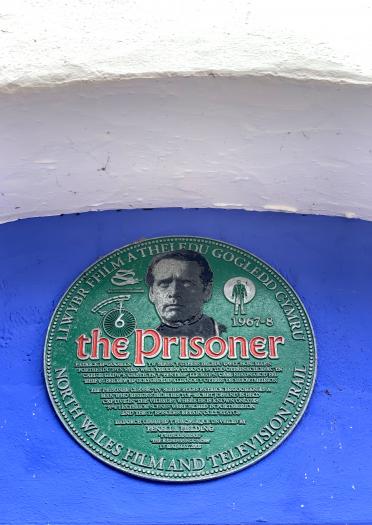 A green round plaque with information about The Prisoner.
