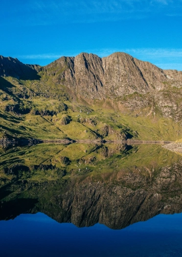 Llyn Llydaw lake on a sunny day with Mount Snowdon  in the background and reflected in the water.