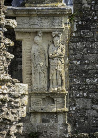 Two carved stone effigies on a castle wall.