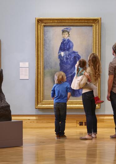 Two adults and two children looking at a painting of a lady in a blue dress in gallery.