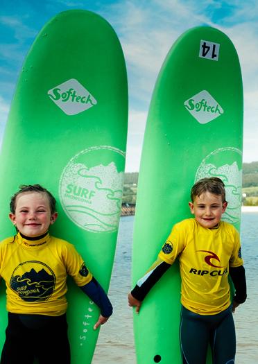 Two young children holding up surf boards.