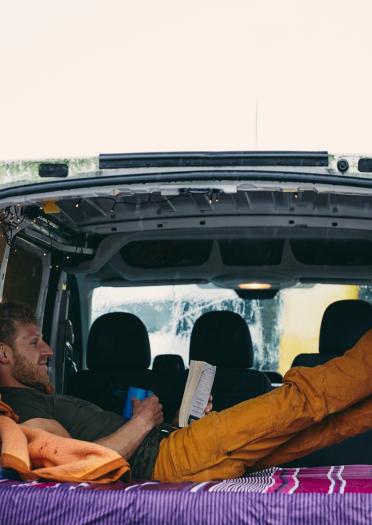 Man relaxing in the back of a traveller van.