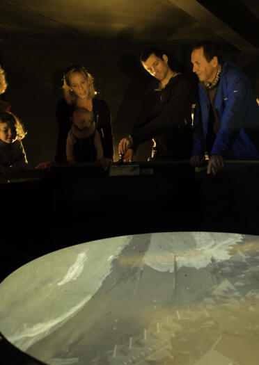 A group of people looking at a camera obscura screen.