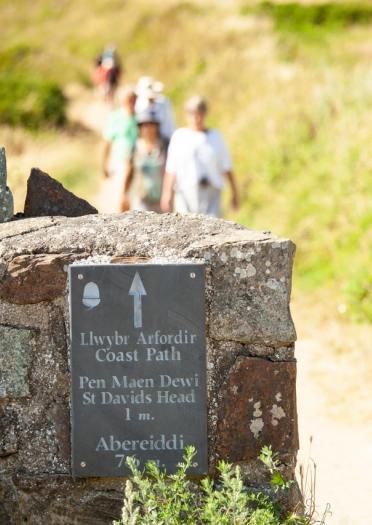 Coast Path sign with people in the background walking the path