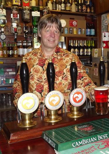 A landlord serving a pint from behind the bar of a pub.