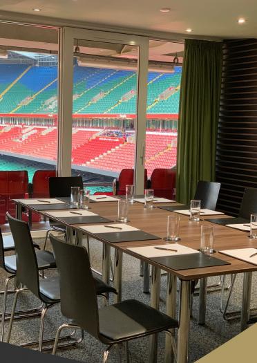 A meeting table set out in a VIP box overlooking a sporting stadium.