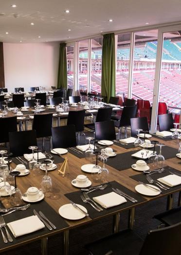 Dining tables set out in a VIP box overlooking a sporting stadium.