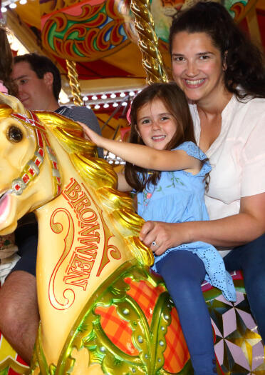 woman and girl on horse on fairground carousel.