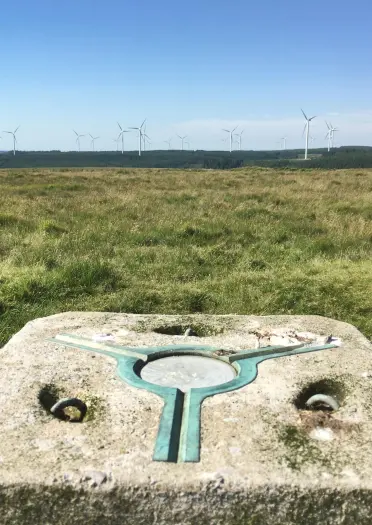 Trig point from which you can view a wind farm.