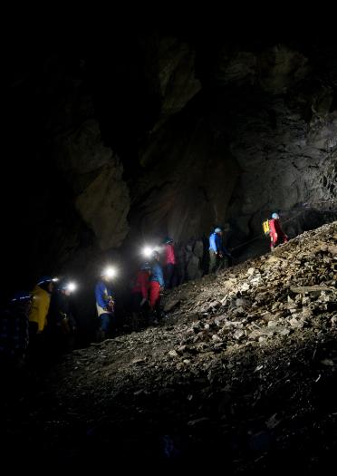 Explorers tied together and climbing up a slate heap in a mine.