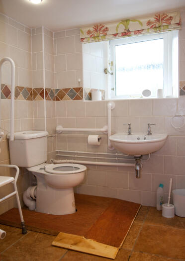 An accessible bathroom with grab rails and ramp.