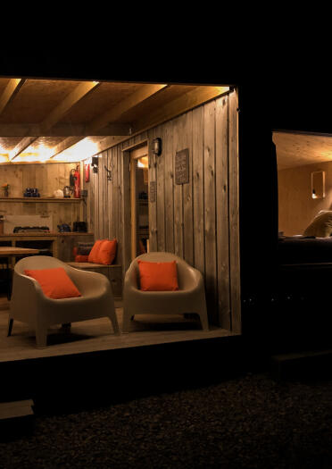 Innenansicht eines Wohn- und Schlafzimmers in einer Holzhütte bei Nacht.