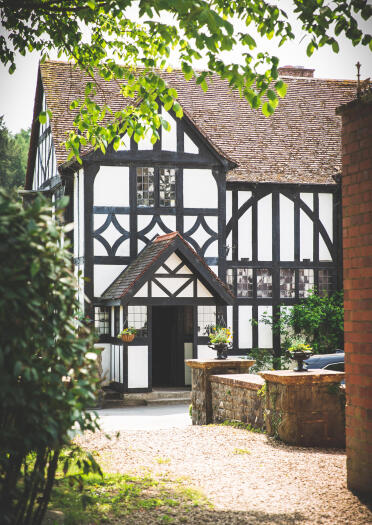 A white painted wooden Tudor-style manor house.