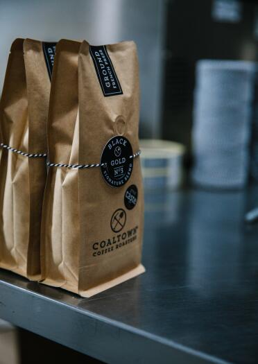 packets of coffee labelled Coaltown on a metal surface.