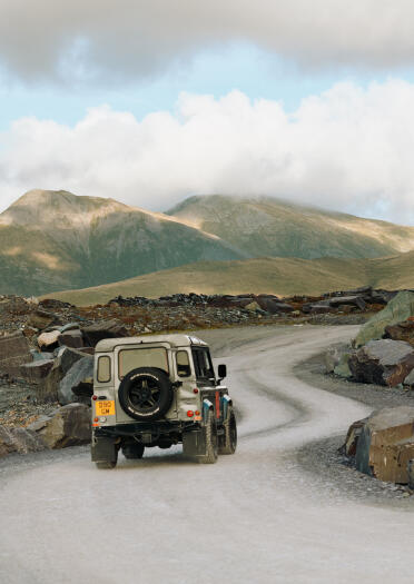 A Land Rover going up a dusty road in a slate quarry.