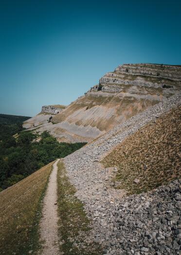 Ein Wanderweg an einem Kalkstein-Steilhang.