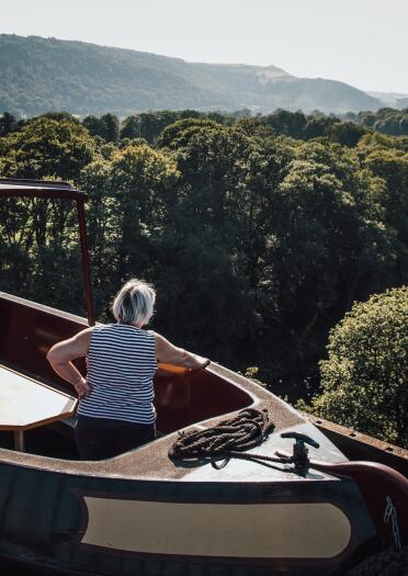 woman on boat on aqueduct, with views of water and countryside.