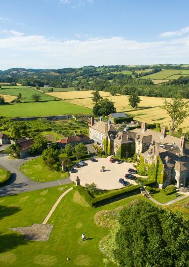 drone shot of stately hall and surrounding countryside.