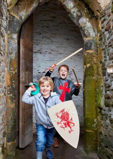 Two children pretending to be knights in a castle. 