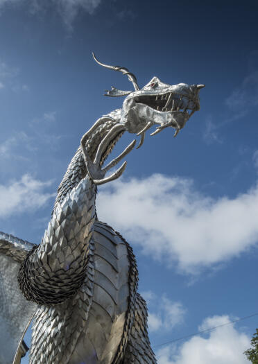 A large steel dragon sculpture in a town centre.