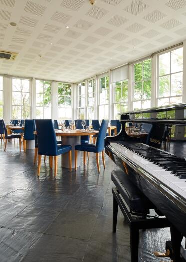 conservatory with piano and tables and chairs.