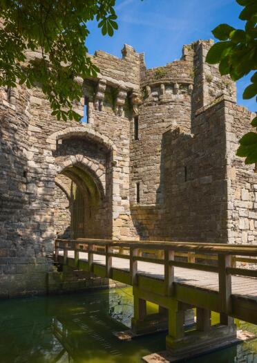 Zugbrücke über einen Wassergraben in ein steineres Eingangstor einer Burg.