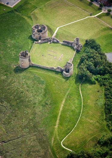 An aerial view of castle ruins surrounded by green fields