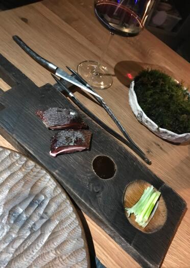 A wooden board with two small pieces of duck and sliced spring onions.