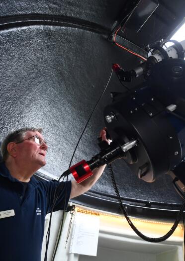 A man adjusting a huge telescope in an astronomy observatory.