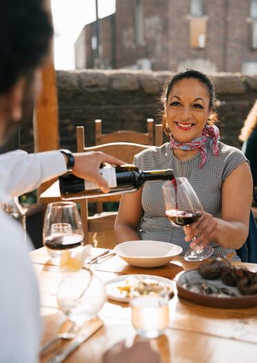 A man pouring a glass of red wine for a woman at a restaurant.