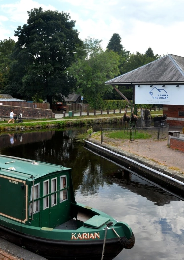 A museum building by a canal, with a green canal boat moored nearby.