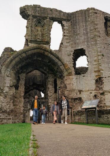 family walking through entrance of castle remains.