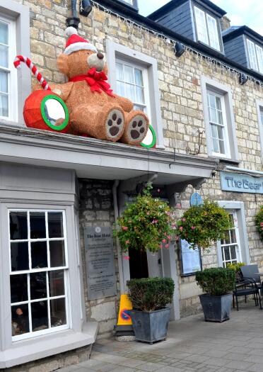 exterior of hotel with large Christmas teddy bear decoration.