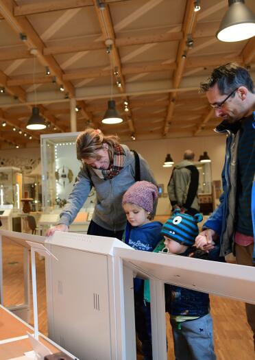 Two adults and two young children looking at museum exhibits.