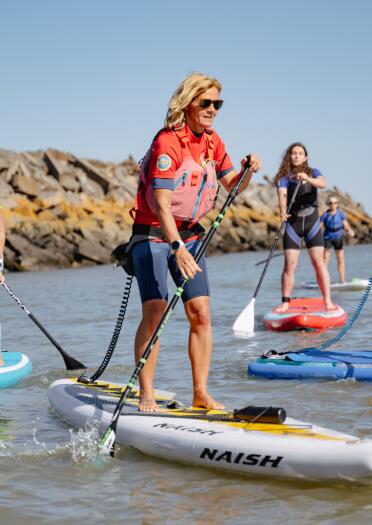 group of women stand up paddleboarding.