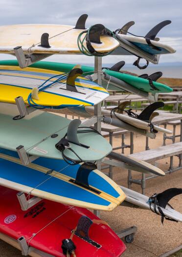 A rack of colourful surfboards on a trailer.
