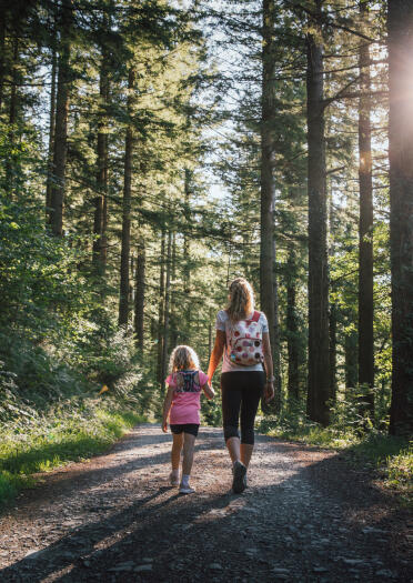 A woman and young child walking along a woodland path.