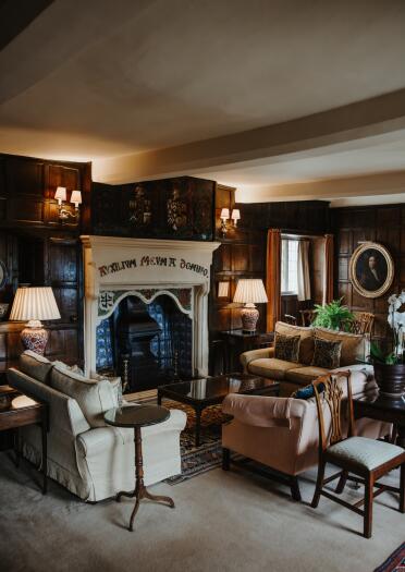 A cosy hotel sitting room with a large fireplace and comfy-looking sofas. 