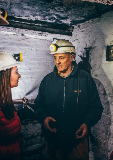 Four adults wearing overalls and hard-hat helmets with head torches on the front.