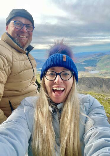 Selfie of two people high up a mountain with views for miles behind them.