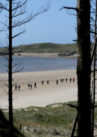 people walking on the beach at Llanddwyn Island.