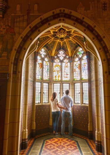 two people standing and staring out of window inside Cardiff Castle.