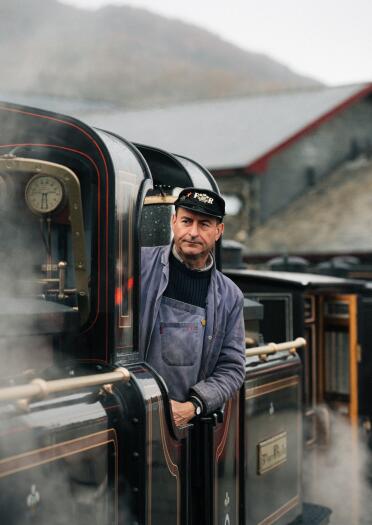 driver of steam train sticking his head out