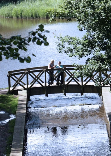 two women stood on bridge over water.