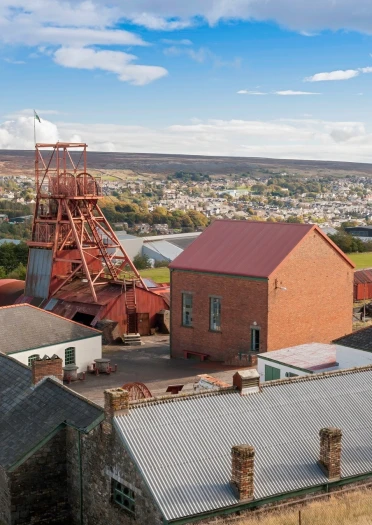 Blick auf den Förderturm und die Nebengebäude von Big Pit mit der Stadt im Hintergrund
